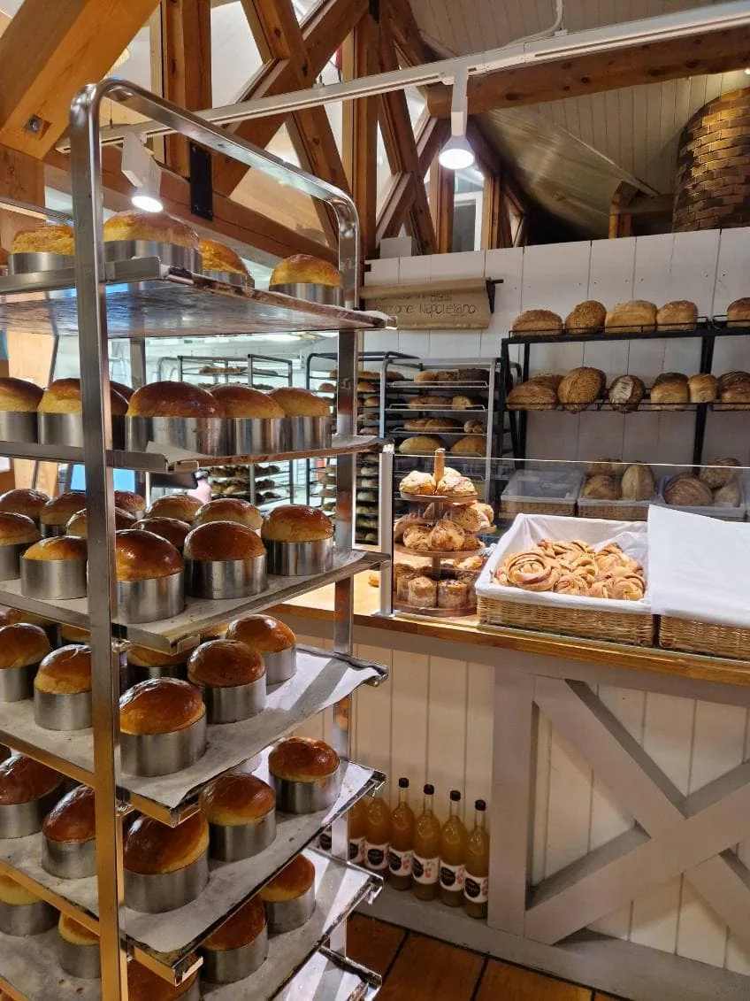 Saftig norsk bakverk og nybakte brød som står på rekke i et bakeri, dekorert med treverk og varme lamper, skaper en innbydende atmosfære.preferert med varm, fersk bakst fra Taffat.no.