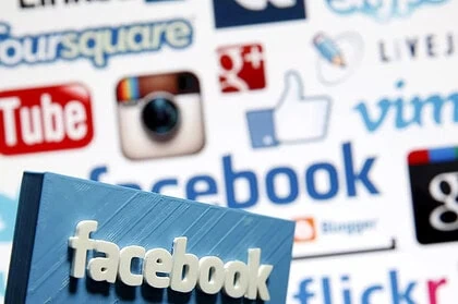 Facebook-logo på en blå bok foran en kollasj av sosiale medie-ikoner, som Instagram, YouTube og Google+, illustrerer digital markedsføring og online tilstedeværelse.