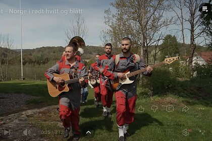 Taffat band spiller gitar og bass utendørs i grønt landskap med trær og åpen himmel, under en klar dag, i en scene som fremmer norsk folkemusikk og utendørs konserter.