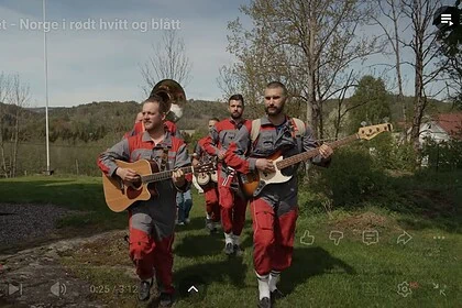Taffat band spiller gitar og bass utendørs i grønt landskap med trær og åpen himmel, under en klar dag, i en scene som fremmer norsk folkemusikk og utendørs konserter.